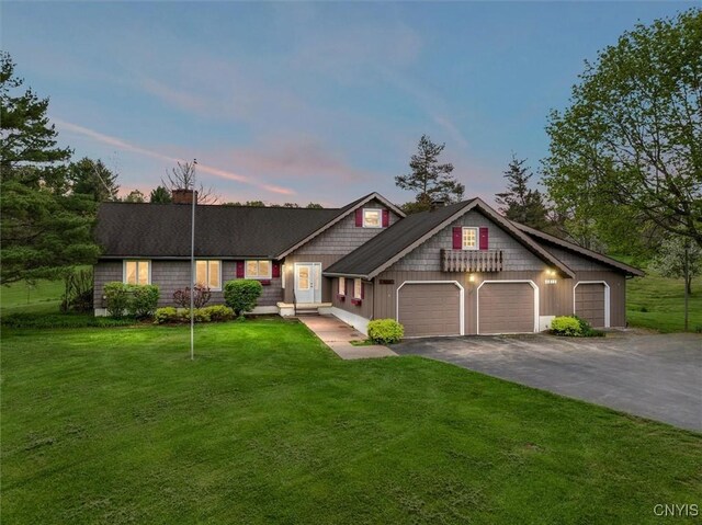 view of front of house with aphalt driveway, an attached garage, a chimney, and a yard