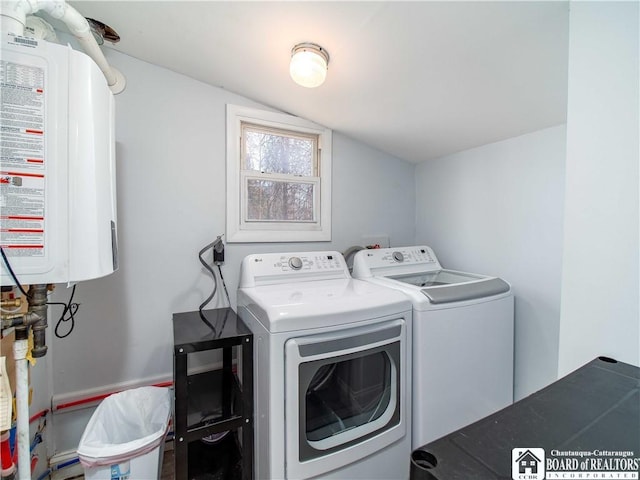 clothes washing area featuring laundry area, water heater, and washer and clothes dryer