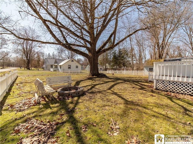 view of yard featuring a wooden deck, an outdoor fire pit, and fence