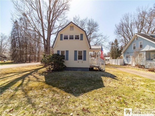 back of house with a gambrel roof, a lawn, and fence