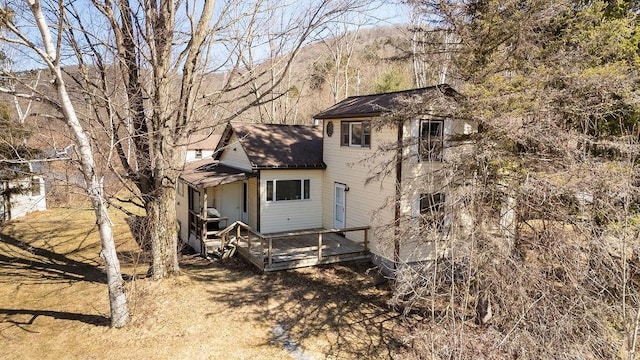 back of house featuring roof with shingles and a deck