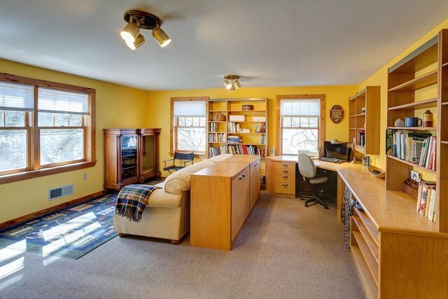home office with baseboards, visible vents, and light carpet