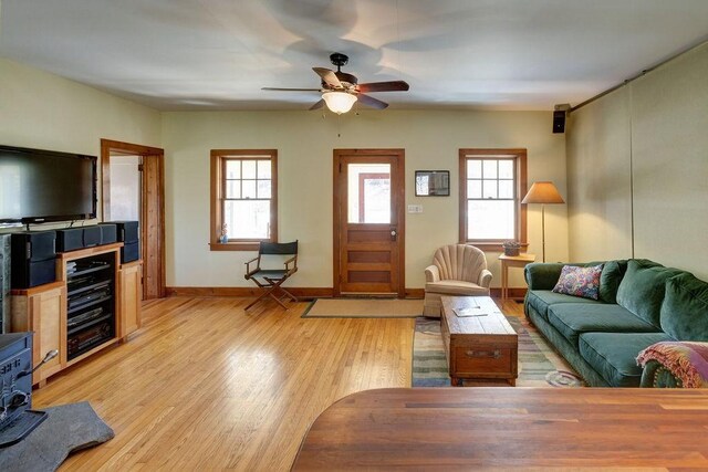 living room featuring baseboards, light wood-type flooring, and ceiling fan