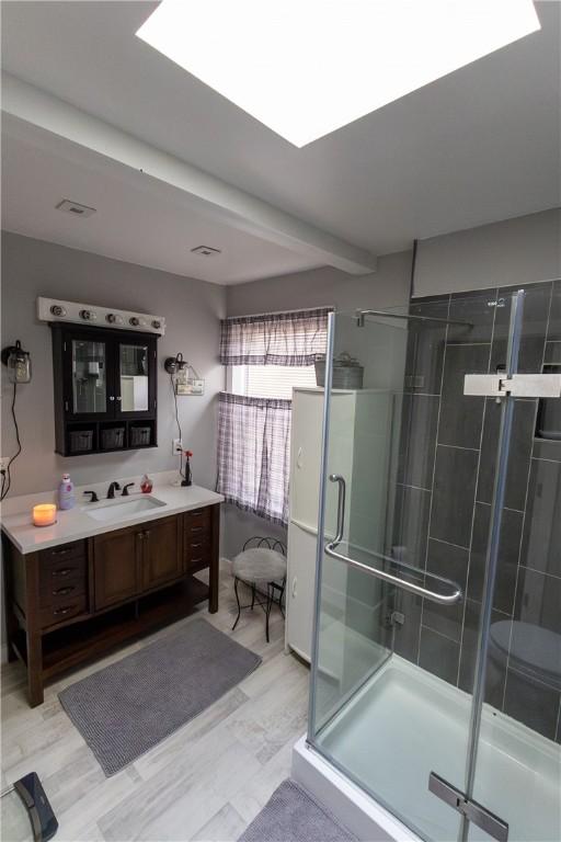 bathroom with a stall shower, vanity, and wood finished floors