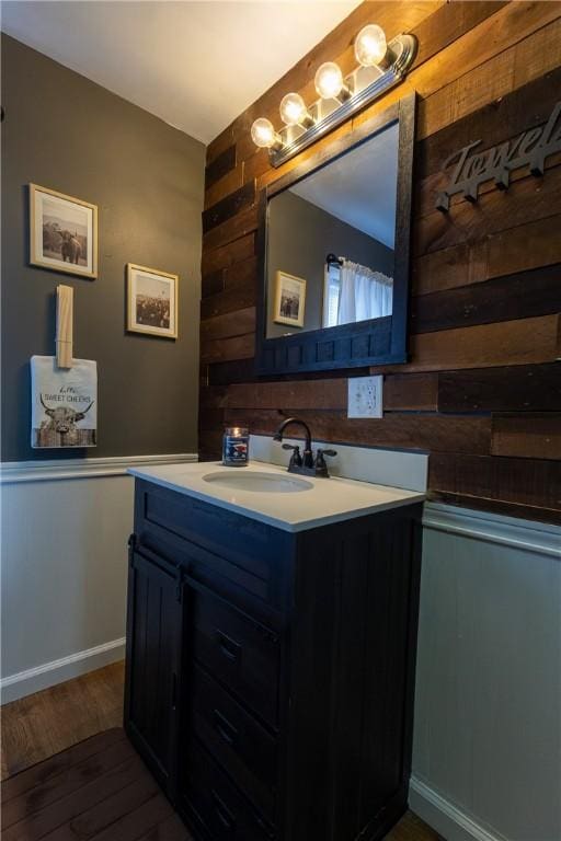 bathroom featuring wood finished floors, wood walls, and vanity