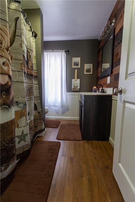 bathroom with curtained shower, vanity, and wood finished floors