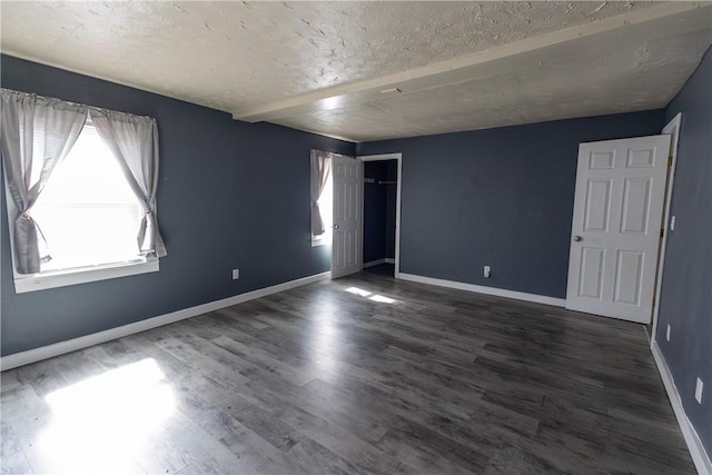 unfurnished room with baseboards, dark wood-style flooring, and a textured ceiling