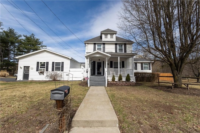 american foursquare style home featuring a front lawn, fence, and covered porch