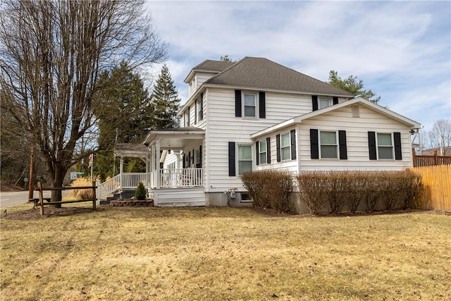 rear view of house featuring a yard, roof with shingles, a porch, and fence