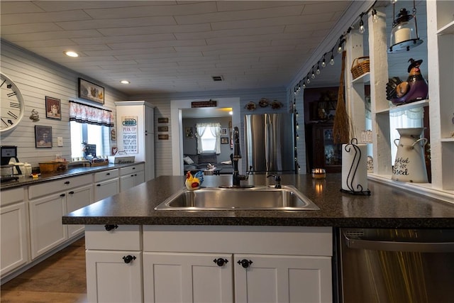 kitchen featuring white cabinetry, dark countertops, appliances with stainless steel finishes, and a sink