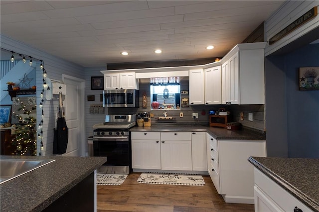 kitchen featuring dark countertops, tasteful backsplash, dark wood-type flooring, stainless steel appliances, and white cabinetry