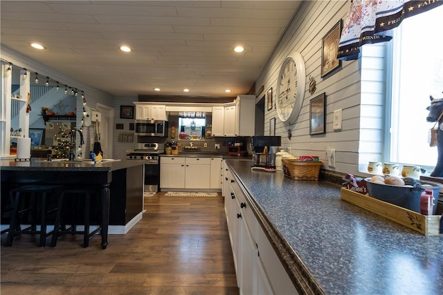kitchen with a sink, stainless steel appliances, dark countertops, and white cabinets