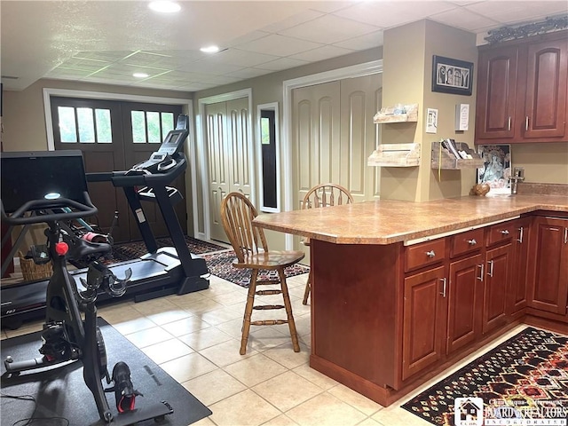 kitchen with light countertops, french doors, a breakfast bar area, a peninsula, and a drop ceiling