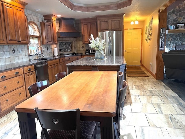 kitchen featuring a sink, a kitchen island, tasteful backsplash, appliances with stainless steel finishes, and custom exhaust hood