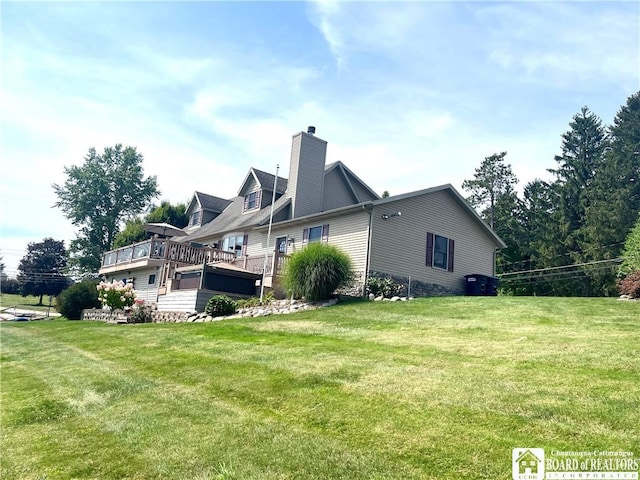 view of side of property with a lawn, a chimney, and a deck