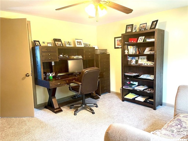 carpeted office space featuring baseboards and a ceiling fan