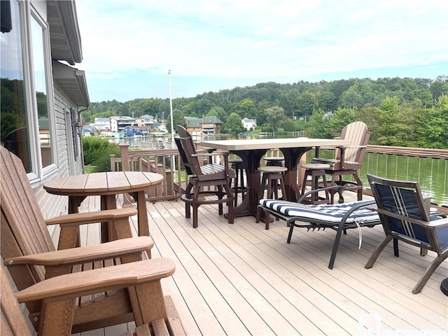 wooden deck with a wooded view and outdoor dining space