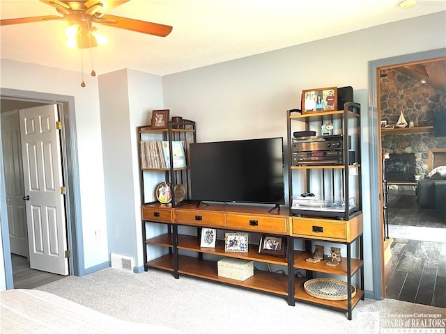 bedroom with a stone fireplace, baseboards, visible vents, and carpet