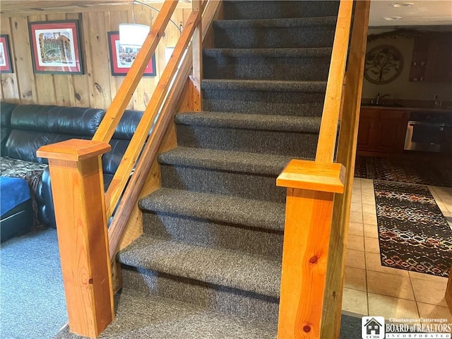 staircase with wood walls and tile patterned floors