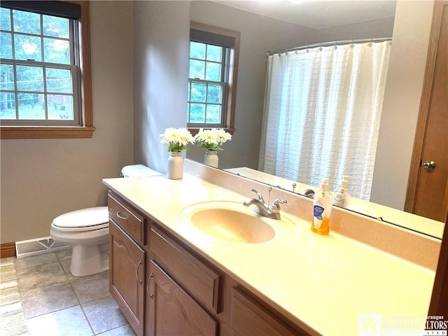 bathroom featuring toilet, plenty of natural light, vanity, and visible vents
