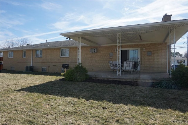 480 Lakeview Ave, Orchard Park, NY 14127 - rear view of house featuring brick siding, a yard, a chimney, an AC wall unit, and a patio area
