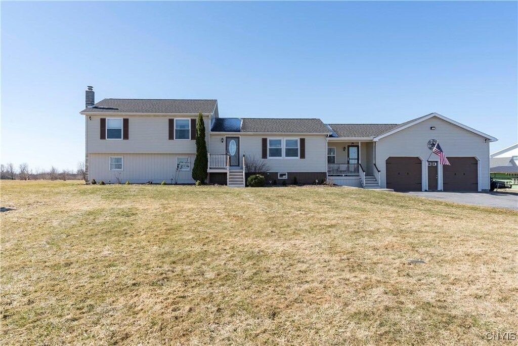 25422 County Route 16, Le Ray, NY 13637 - split level home with an attached garage, a chimney, driveway, and a front lawn