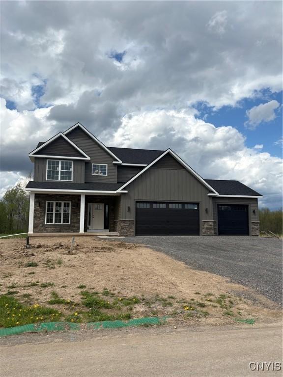 3515 Tall Tree Ln, Lysander, NY 13027 - view of front of property with board and batten siding, driveway, covered porch, a garage, and stone siding