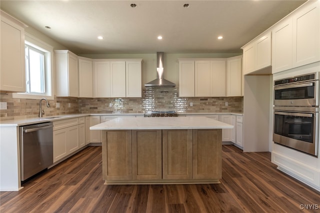3515 Tall Tree Ln, Lysander, NY 13027 - kitchen with appliances with stainless steel finishes, wall chimney range hood, a kitchen island, tasteful backsplash, and white cabinetry