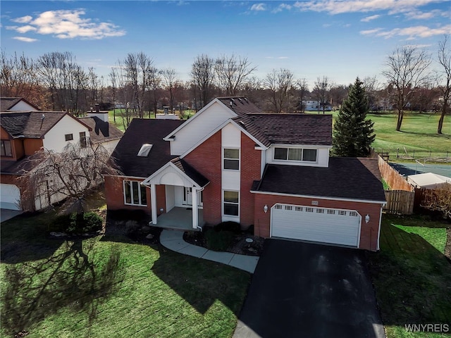 traditional home featuring a garage, driveway, a front lawn, and fence