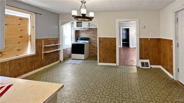 kitchen featuring a wainscoted wall, range with electric stovetop, and wooden walls