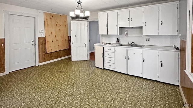 kitchen with a chandelier, light countertops, tile patterned floors, white cabinetry, and a sink