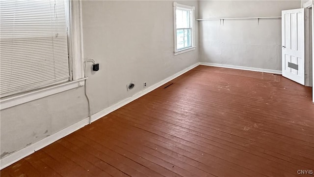 empty room with hardwood / wood-style floors, baseboards, and visible vents