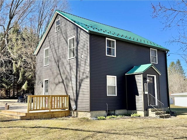 view of front of home with entry steps, a front lawn, a wooden deck, and metal roof