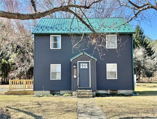 colonial-style house with entry steps, metal roof, and a front yard