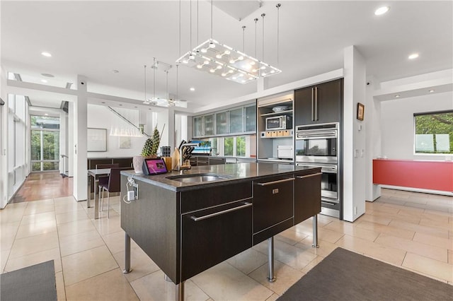10289-10288 Whispering Wind Trl, Corning, NY 14830 - kitchen with stainless steel double oven, dark countertops, recessed lighting, decorative light fixtures, and an island with sink