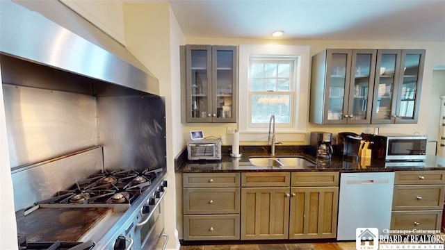 kitchen featuring glass insert cabinets, white dishwasher, dark stone counters, stainless steel microwave, and a sink