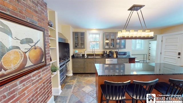 kitchen with wall chimney range hood, stone finish flooring, white dishwasher, a sink, and stainless steel microwave