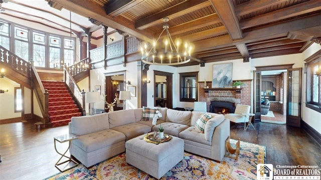 living room featuring an inviting chandelier, a brick fireplace, wood finished floors, baseboards, and wooden ceiling