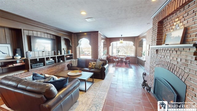 tiled living room with crown molding, a textured ceiling, brick wall, and a fireplace