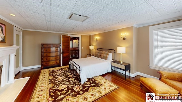 bedroom featuring baseboards, ornamental molding, wood finished floors, and visible vents