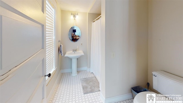 full bathroom featuring baseboards and toilet