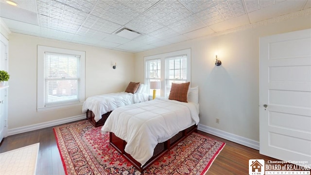 bedroom featuring baseboards, multiple windows, and wood finished floors