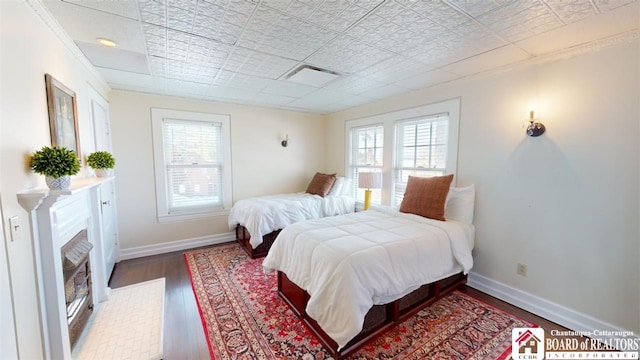 bedroom with baseboards, wood finished floors, and multiple windows
