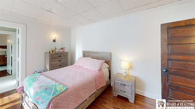 bedroom featuring crown molding, baseboards, and wood finished floors