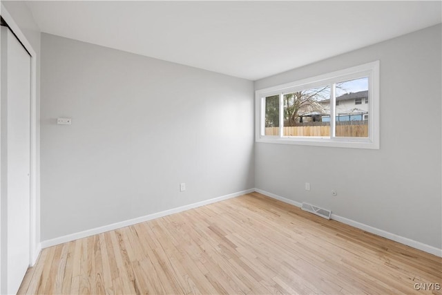 unfurnished room featuring wood finished floors, baseboards, and visible vents
