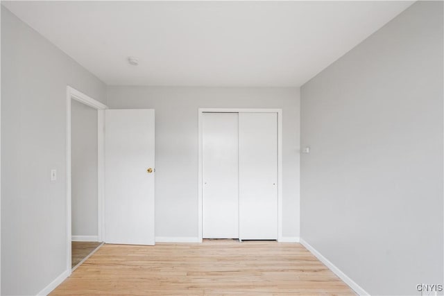 unfurnished bedroom featuring baseboards, a closet, and light wood-style floors