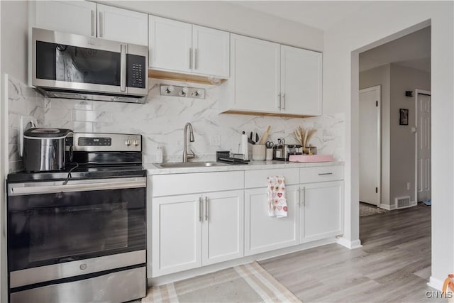 kitchen featuring light countertops, a sink, appliances with stainless steel finishes, visible vents, and white cabinets