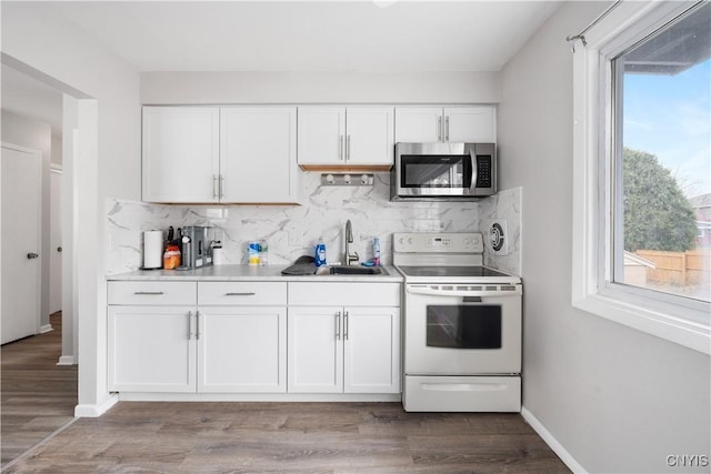 kitchen with stainless steel microwave, white electric range oven, a sink, and white cabinetry