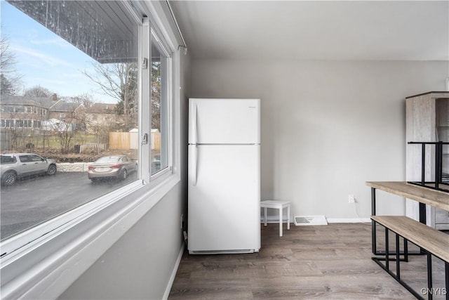 kitchen featuring freestanding refrigerator, visible vents, baseboards, and wood finished floors