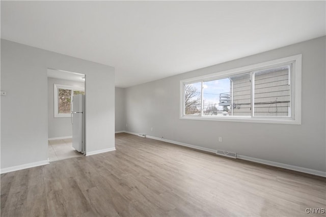 empty room with baseboards, visible vents, and wood finished floors